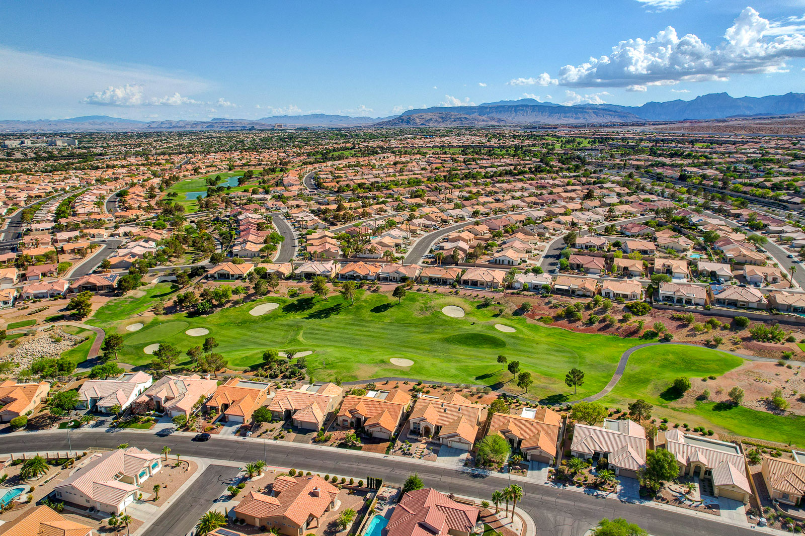 Aerial view of a Sun City Summerlin golf fairway winding through the neighborhood with mountains beyond
